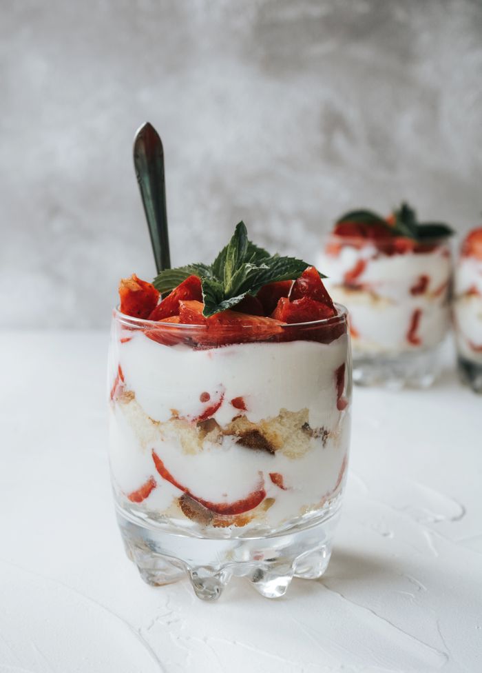 gallery-5 Close-up of a creamy strawberry yogurt parfait with mint garnish in a clear glass.
